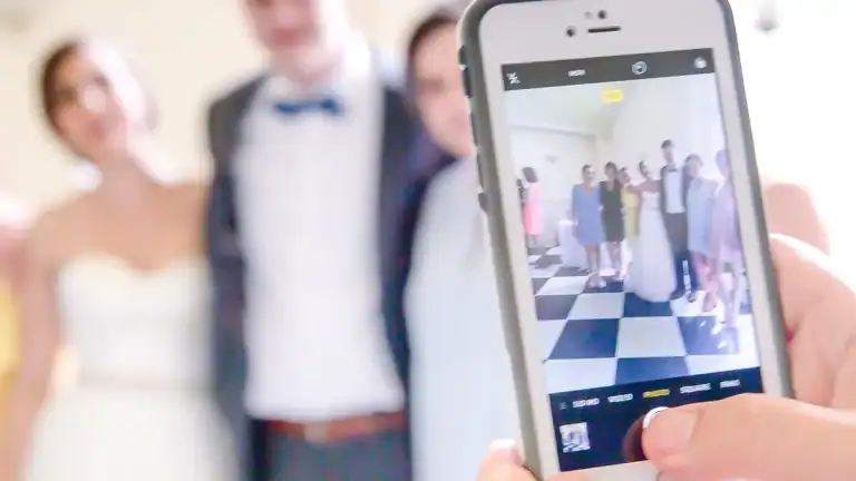 A guest's phone held up at the reception, photographing the wedding party to upload to the couple's takeNplace album