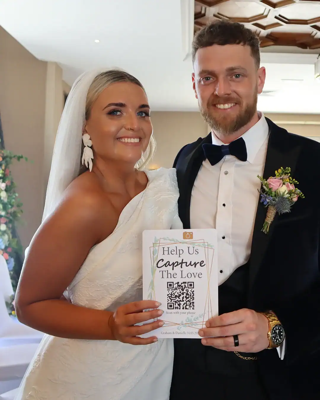 Graham and Danielle holding their Capture the Love wedding QR code card at their reception