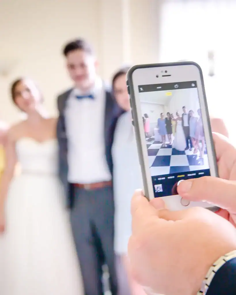 Guest holding up a phone to photograph the wedding party, ready to upload to the couple's takeNplace gallery